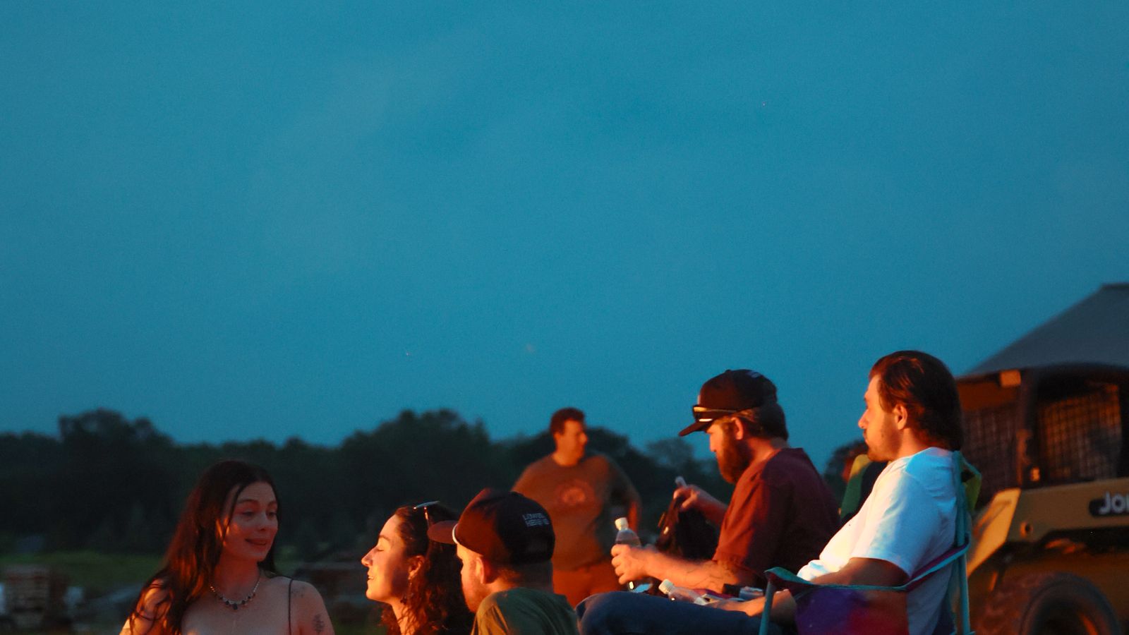 Friends talking in the firelight at a Lowell party at dusk