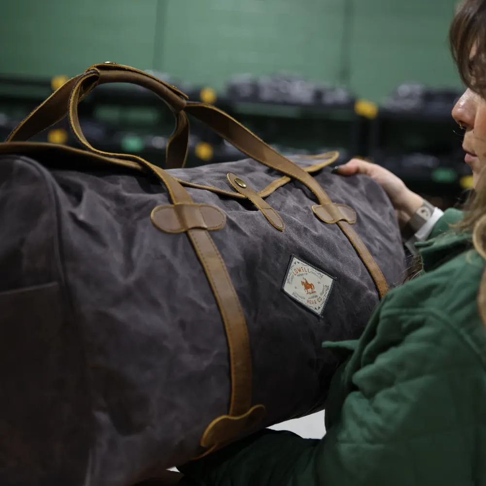 A woman in a green jacket carrying the Wax Canvas Duffel Bag